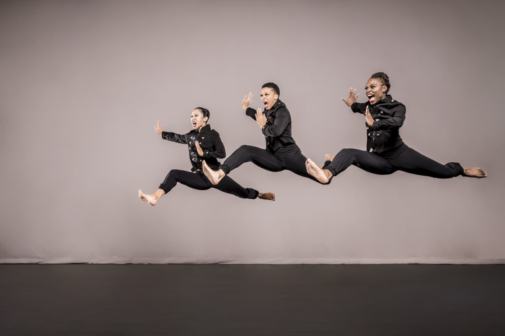 Three dancers leaping in unison.